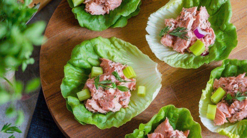 Fresh butter lettuce cups filled with creamy tuna salad, garnished with dill, cherry tomatoes, and avocado slices