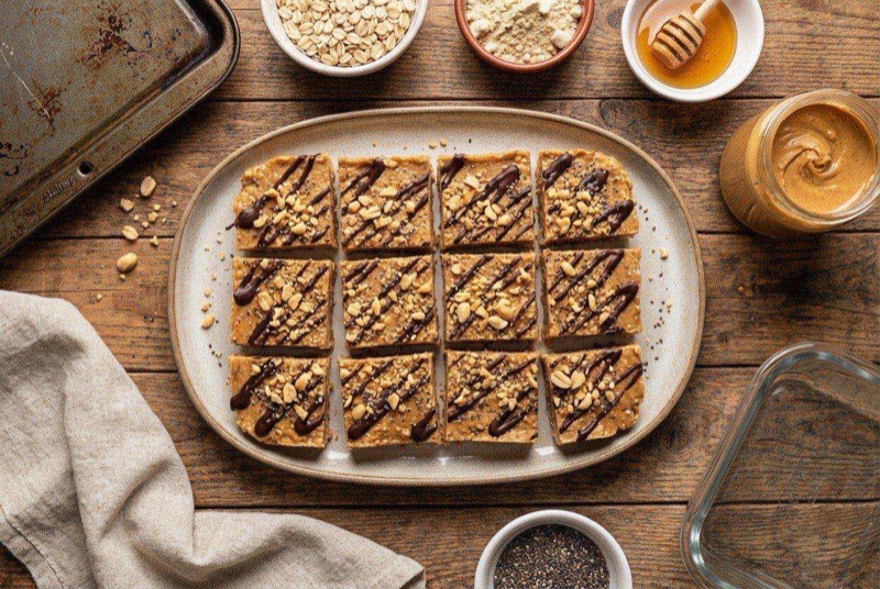 Sliced no-bake peanut butter protein bars with visible oats and chocolate chips on parchment paper