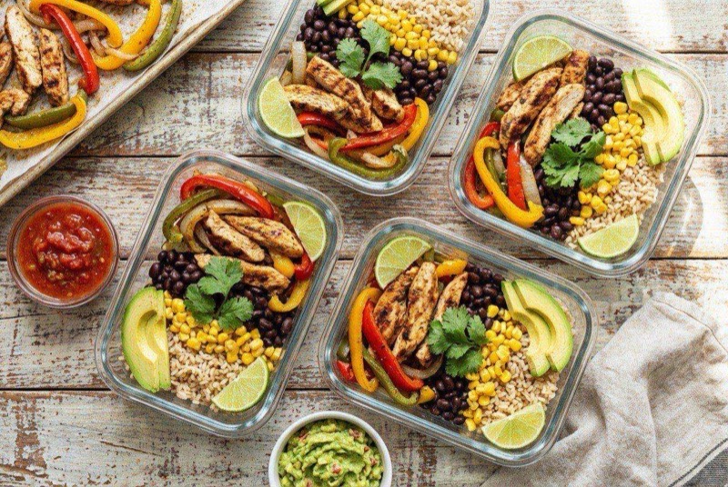 Sheet pan loaded with seasoned chicken strips and charred fajita peppers and onions