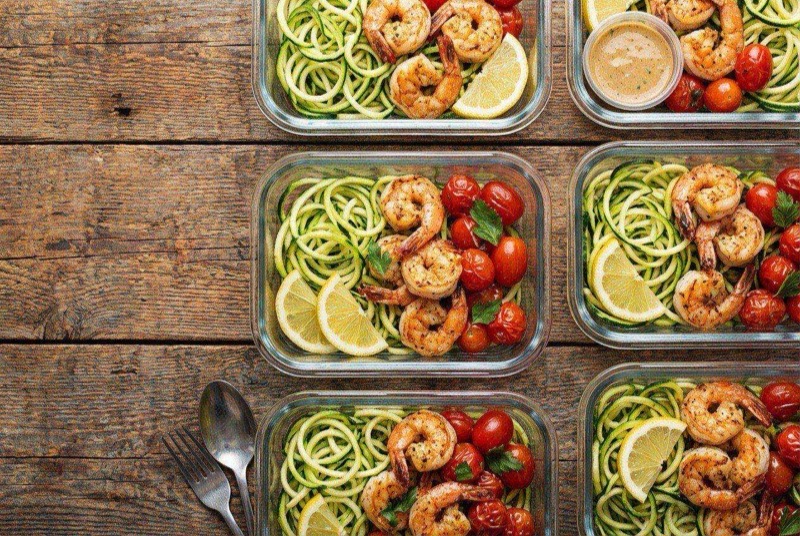 Garlic shrimp nestled in spiralized zucchini noodles with lemon and Parmesan in a white bowl