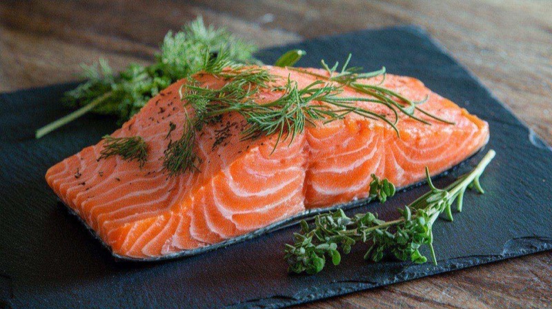 Baked salmon fillets topped with lemon slices and fresh dill, served with roasted asparagus and brown rice