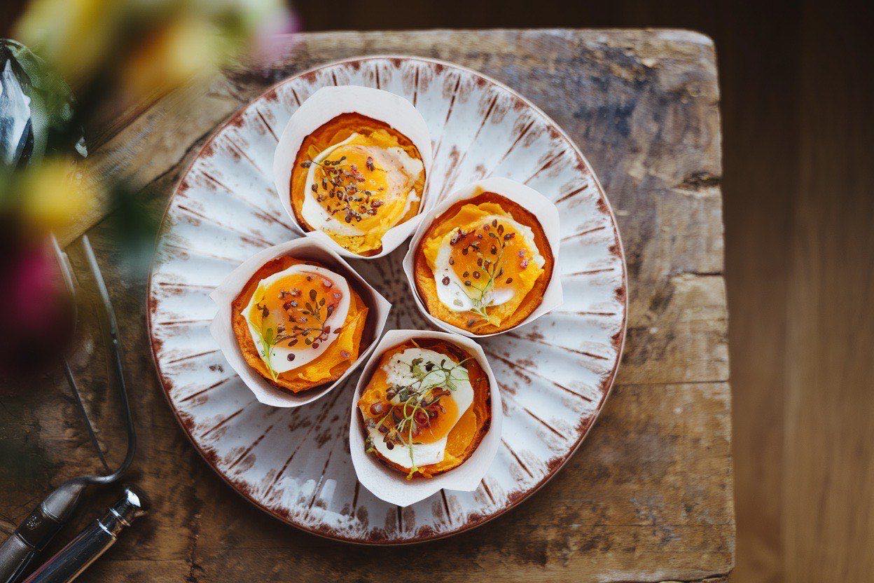 Golden-topped sweet potato egg muffins cooling on a wire rack with a muffin tin in the background