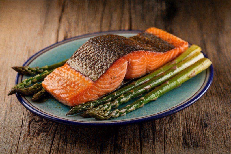 Dijon-crusted salmon fillet alongside green asparagus spears on a white plate