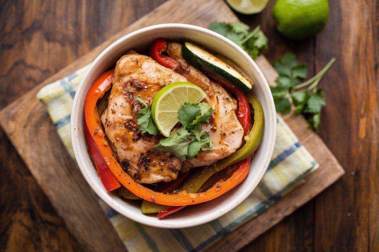 Colorful chicken fajita bowl with roasted peppers and onions over brown rice